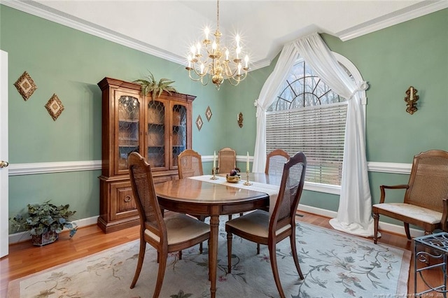 dining space with light hardwood / wood-style floors, a wealth of natural light, ornamental molding, and an inviting chandelier