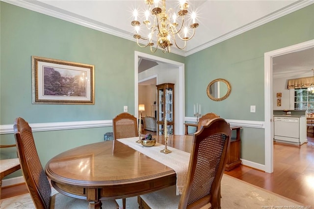 dining area with light wood-type flooring, a notable chandelier, and crown molding