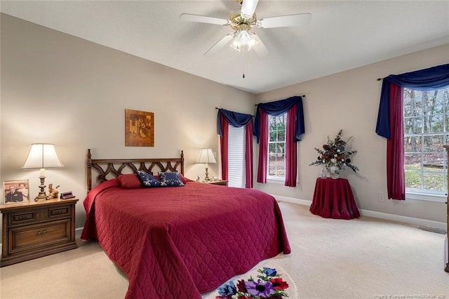 bedroom featuring ceiling fan, light colored carpet, and multiple windows