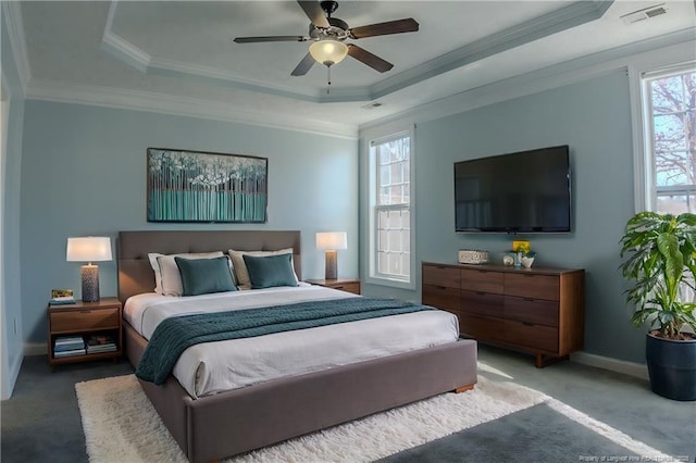 bedroom featuring multiple windows, a tray ceiling, crown molding, and ceiling fan