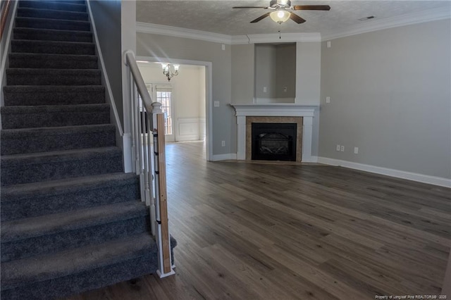 staircase featuring hardwood / wood-style flooring, crown molding, a tile fireplace, and a textured ceiling