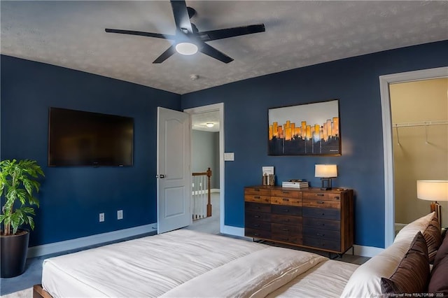 bedroom featuring a walk in closet, ceiling fan, light carpet, a textured ceiling, and a closet