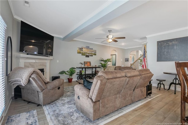 living room with ceiling fan, a tile fireplace, crown molding, and light hardwood / wood-style flooring