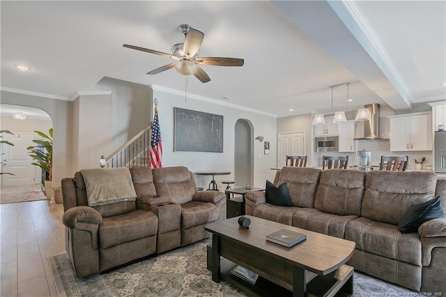 living room featuring ceiling fan, crown molding, and light wood-type flooring