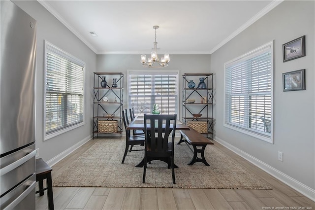 dining area with light hardwood / wood-style flooring, crown molding, and a notable chandelier