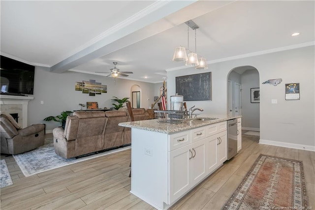 kitchen featuring light wood-type flooring, white cabinets, a kitchen island with sink, and light stone counters