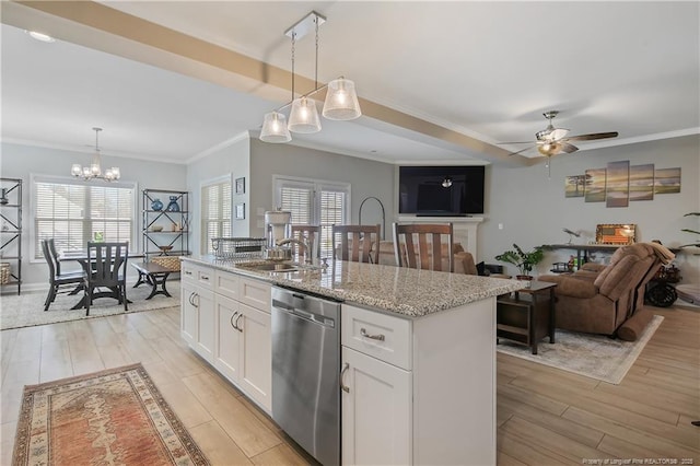 kitchen featuring ceiling fan with notable chandelier, white cabinets, an island with sink, sink, and stainless steel dishwasher