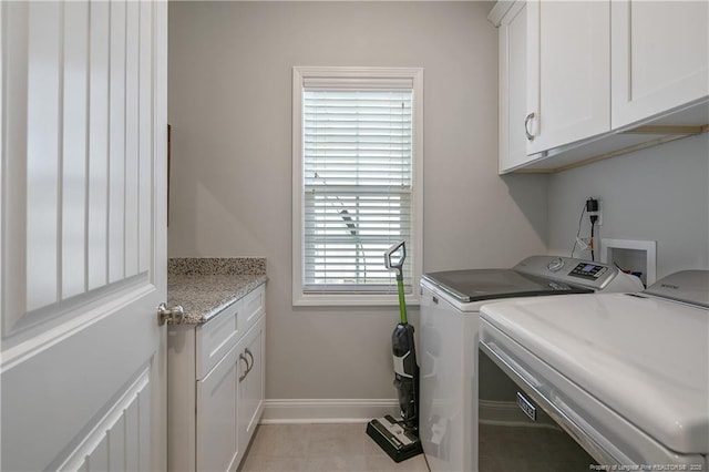 washroom featuring light tile patterned floors, plenty of natural light, washing machine and clothes dryer, and cabinets