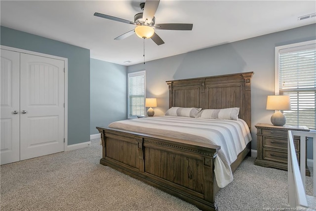 carpeted bedroom featuring ceiling fan, multiple windows, and a closet