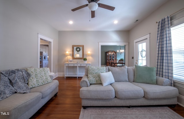 living room featuring ceiling fan with notable chandelier, plenty of natural light, and dark hardwood / wood-style flooring