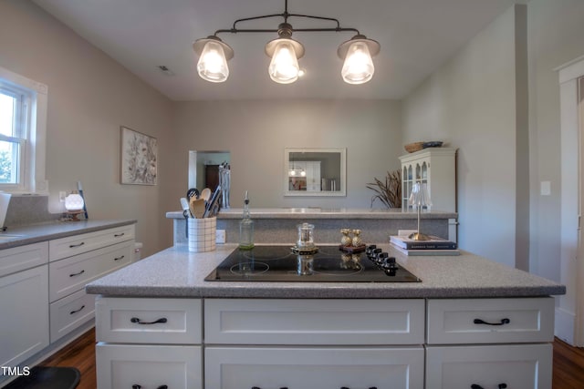 kitchen with decorative light fixtures, dark hardwood / wood-style floors, black electric stovetop, and white cabinetry