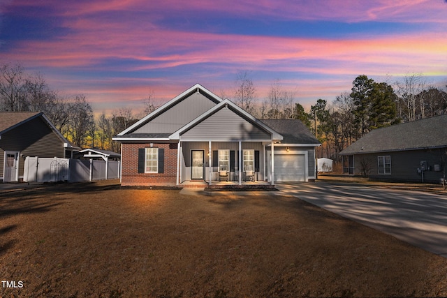 view of front of property featuring a porch, a garage, and a lawn