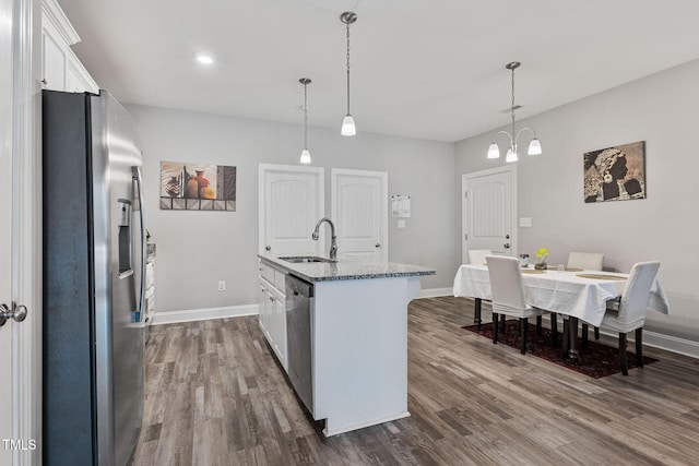 kitchen with white cabinetry, a kitchen island with sink, hanging light fixtures, sink, and appliances with stainless steel finishes