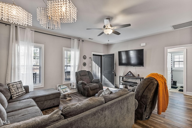 living room featuring hardwood / wood-style floors, a healthy amount of sunlight, and ceiling fan with notable chandelier