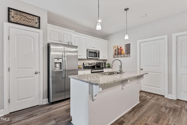 kitchen with appliances with stainless steel finishes, hanging light fixtures, an island with sink, sink, and white cabinetry