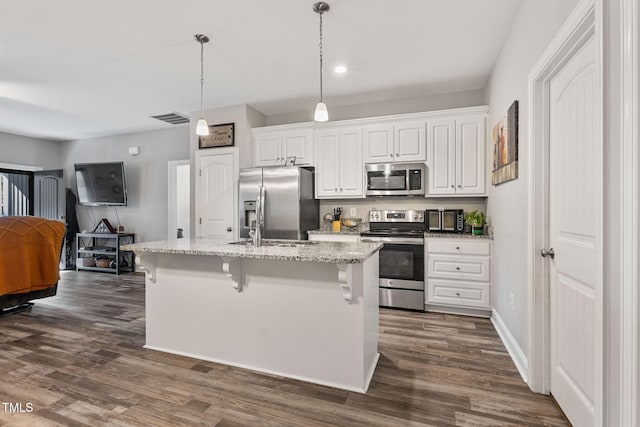 kitchen featuring a breakfast bar area, stainless steel appliances, pendant lighting, white cabinetry, and a kitchen island with sink