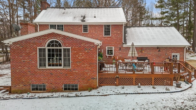 snow covered back of property with a wooden deck