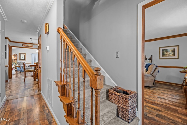 stairway with hardwood / wood-style floors and crown molding