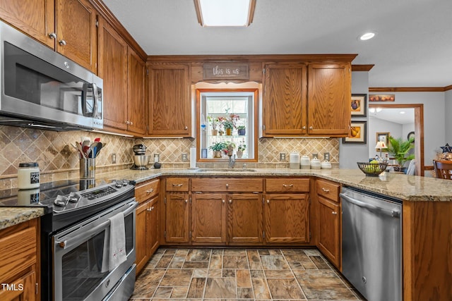 kitchen featuring light stone counters, sink, kitchen peninsula, and stainless steel appliances