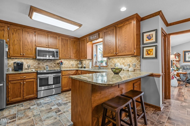 kitchen featuring appliances with stainless steel finishes, backsplash, light stone counters, and sink