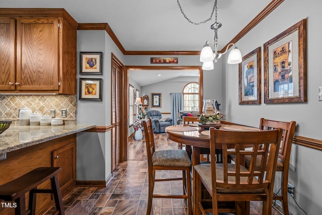 dining area featuring lofted ceiling and crown molding