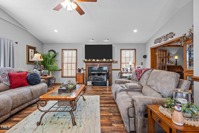 living room featuring ceiling fan, dark hardwood / wood-style floors, lofted ceiling, a fireplace, and a textured ceiling