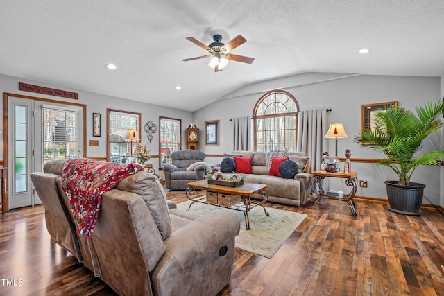 living room with ceiling fan, vaulted ceiling, dark hardwood / wood-style floors, and a textured ceiling