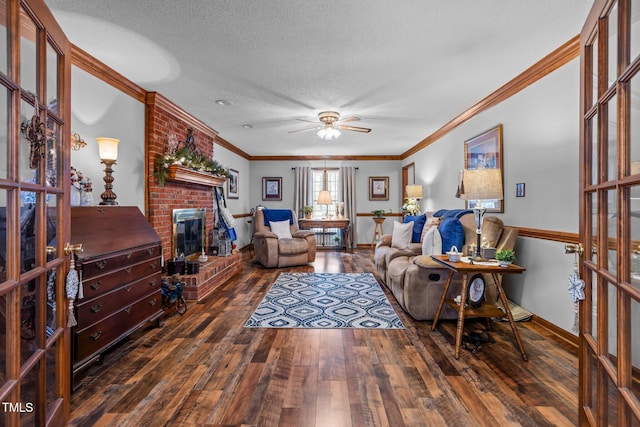 living room with a textured ceiling, dark wood-type flooring, a fireplace, ceiling fan, and crown molding