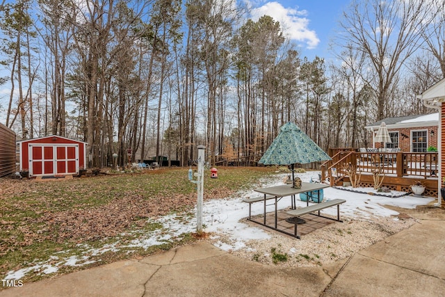 snow covered patio featuring a storage shed and a wooden deck