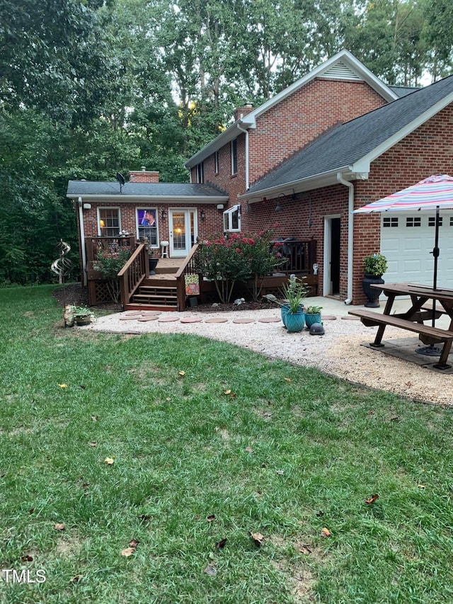 rear view of property with a garage, a deck, and a yard