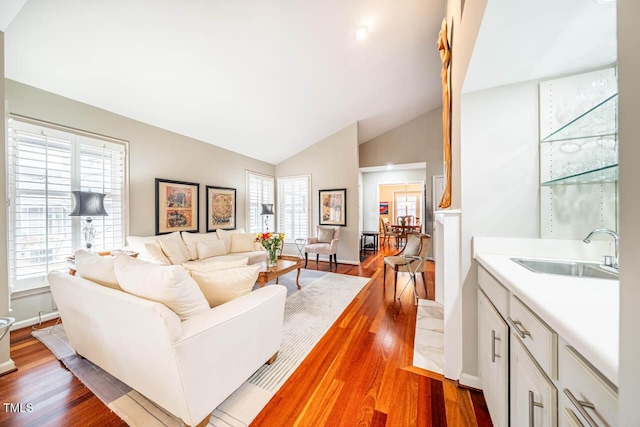 living room featuring sink, wood-type flooring, and high vaulted ceiling