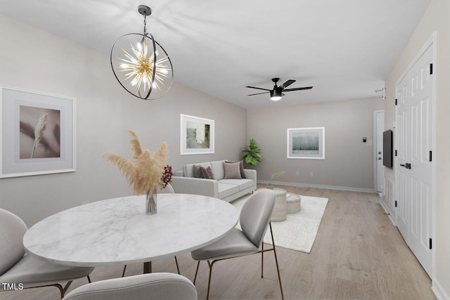 dining space with ceiling fan with notable chandelier and light hardwood / wood-style floors