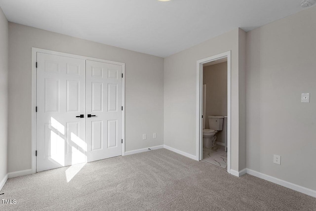 unfurnished bedroom featuring light carpet, a closet, and ensuite bath