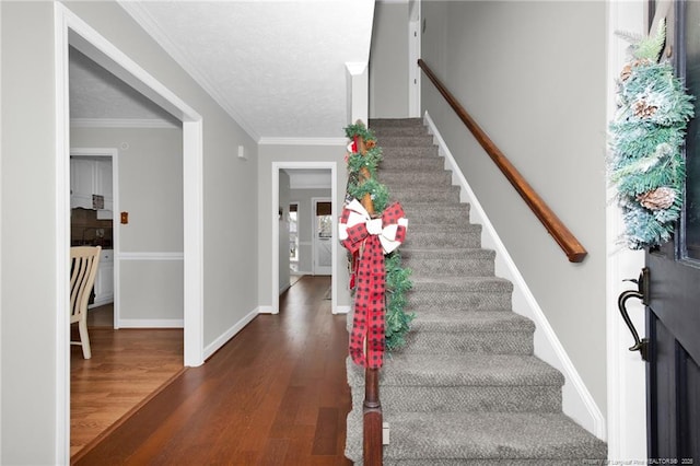 stairway featuring wood-type flooring, crown molding, and a textured ceiling