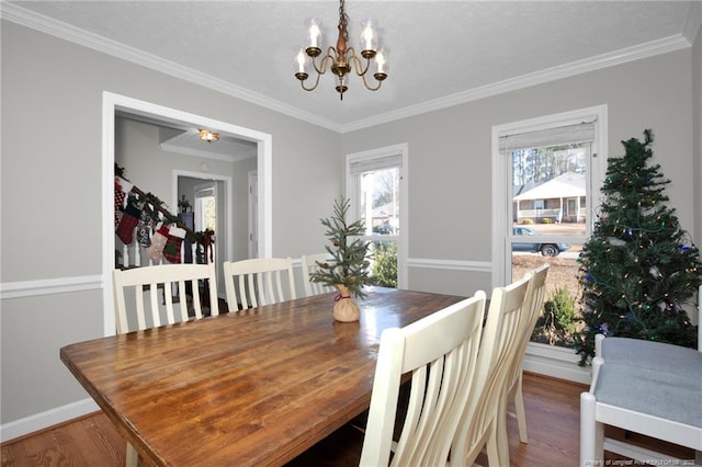 dining space featuring an inviting chandelier, hardwood / wood-style floors, crown molding, and plenty of natural light