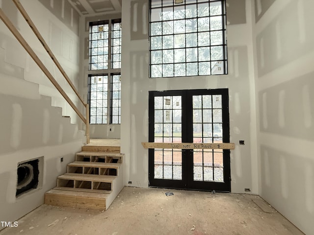 foyer entrance featuring a high ceiling, stairway, and french doors