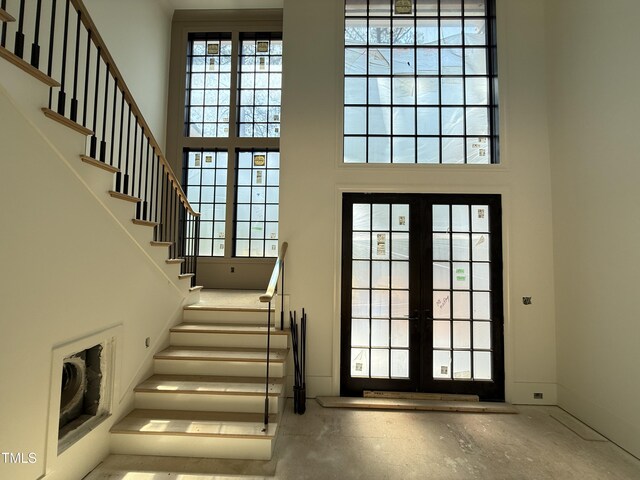entryway with french doors, stairs, and a high ceiling