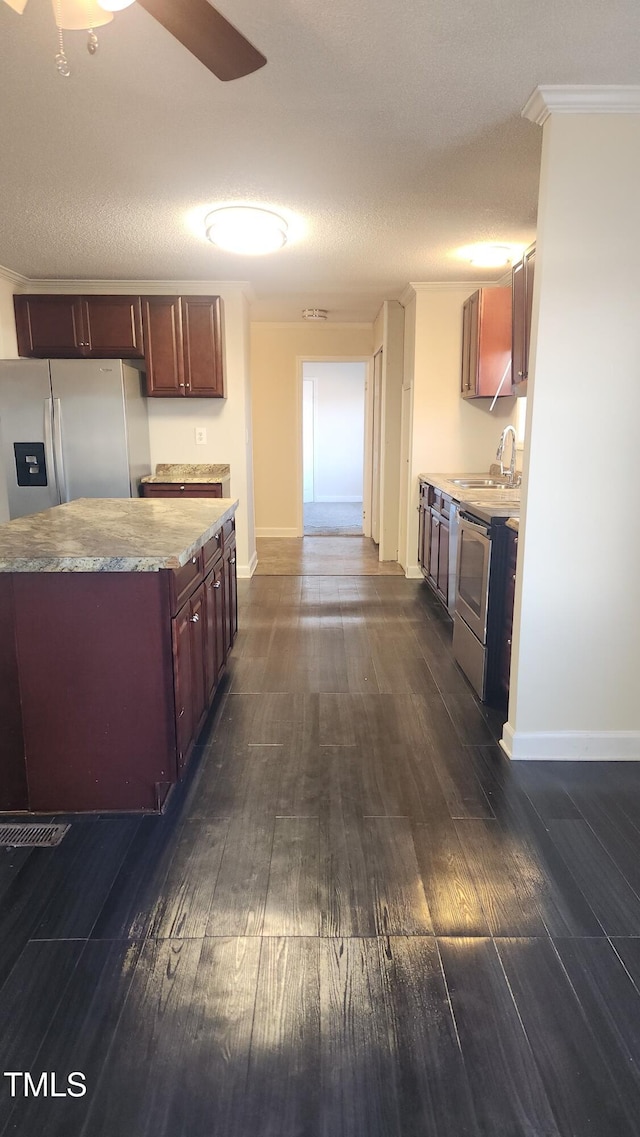 kitchen with sink, dark hardwood / wood-style flooring, stainless steel appliances, crown molding, and a textured ceiling