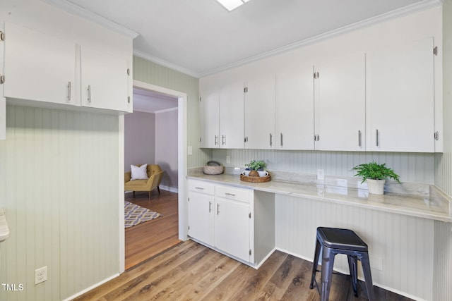 kitchen with white cabinets, crown molding, and hardwood / wood-style flooring