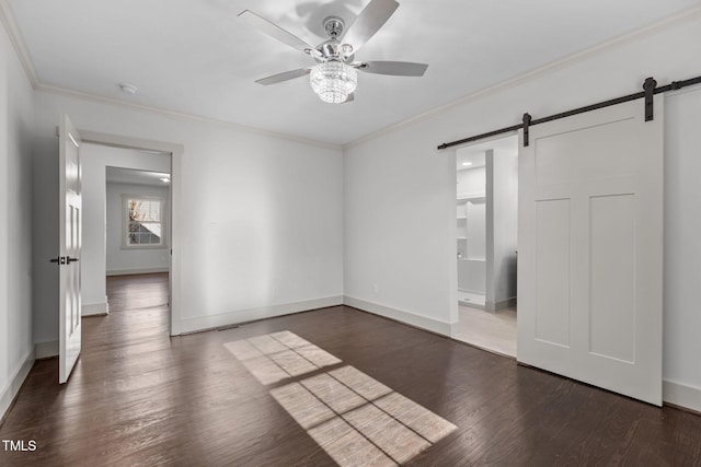 empty room with crown molding, dark hardwood / wood-style floors, ceiling fan, and a barn door