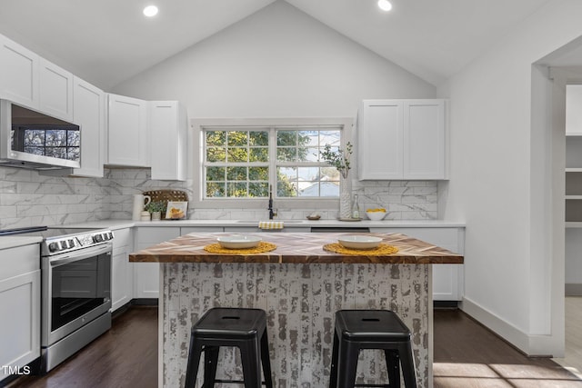 kitchen with a breakfast bar area, white cabinetry, appliances with stainless steel finishes, and butcher block countertops