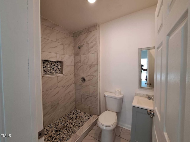 bathroom featuring toilet, vanity, and tiled shower