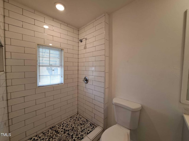 bathroom featuring a tile shower and toilet