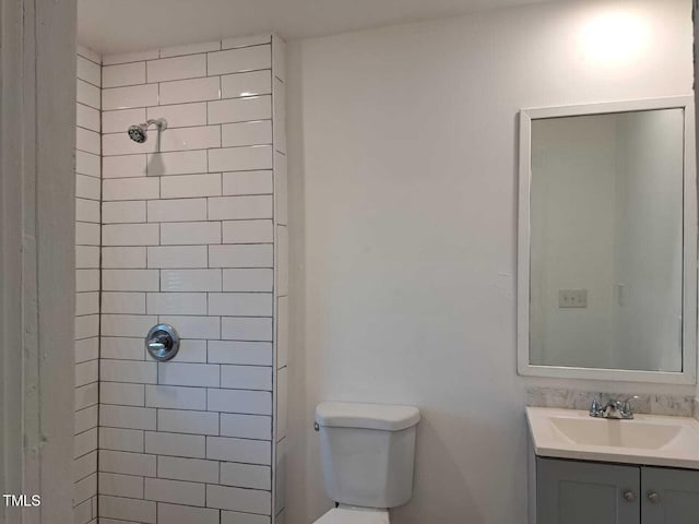 bathroom with vanity, toilet, and a tile shower