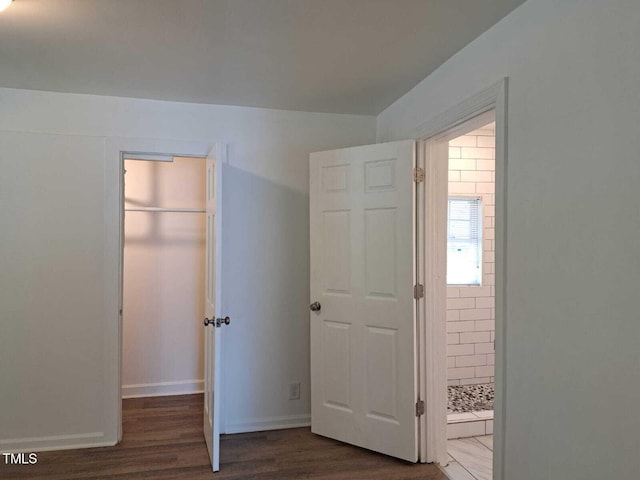 unfurnished bedroom with dark wood-type flooring, a closet, and a walk in closet