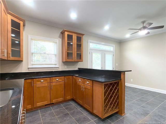 kitchen featuring ceiling fan, plenty of natural light, dark stone counters, and ornamental molding