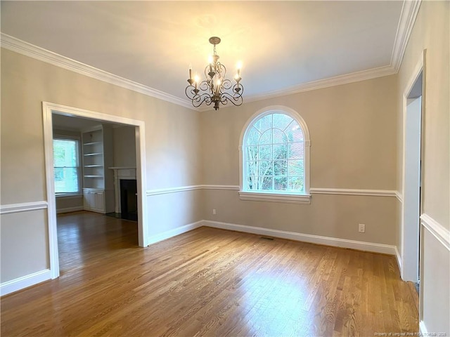 unfurnished room featuring crown molding, wood-type flooring, and a notable chandelier