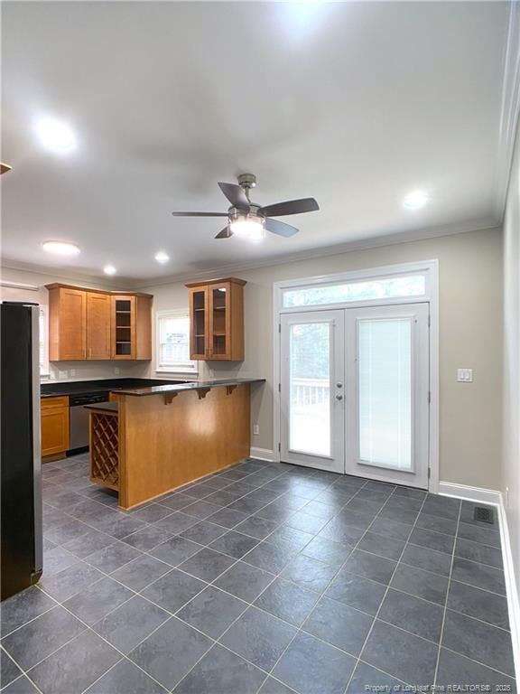 kitchen with ceiling fan, kitchen peninsula, a kitchen bar, stainless steel appliances, and ornamental molding