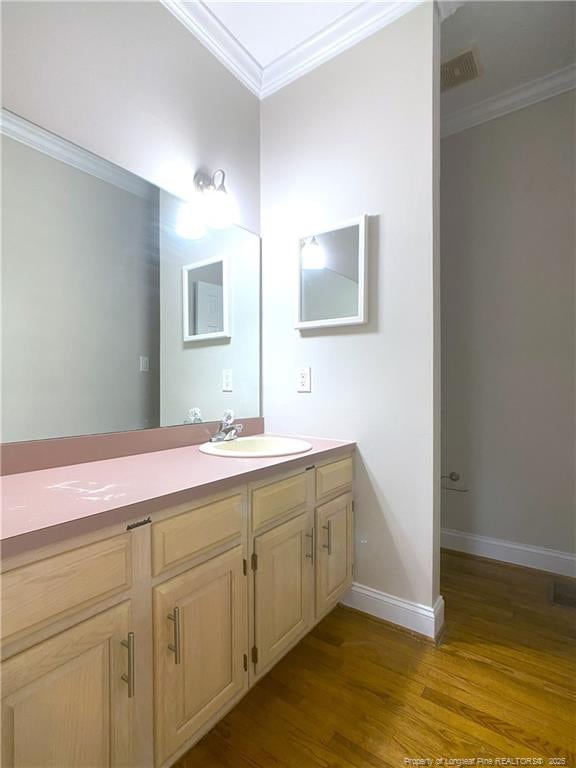 bathroom featuring ornamental molding, hardwood / wood-style flooring, and vanity