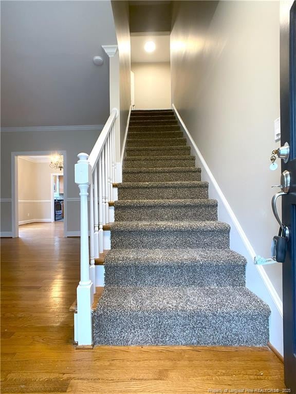 stairway featuring hardwood / wood-style floors and crown molding